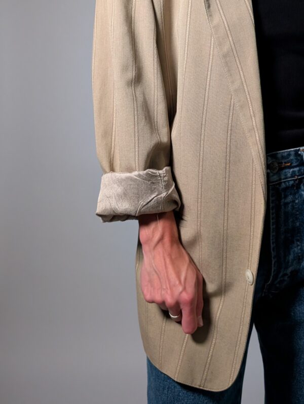 Sand stripe 02 Vintage beige blazer met subtiele verticale glansstrepen, klassieke revers en rechte licht oversized pasvorm.