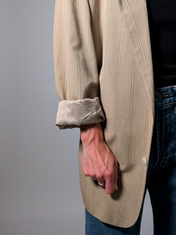 Vintage beige blazer met subtiele verticale glansstrepen, klassieke revers en rechte licht oversized pasvorm.