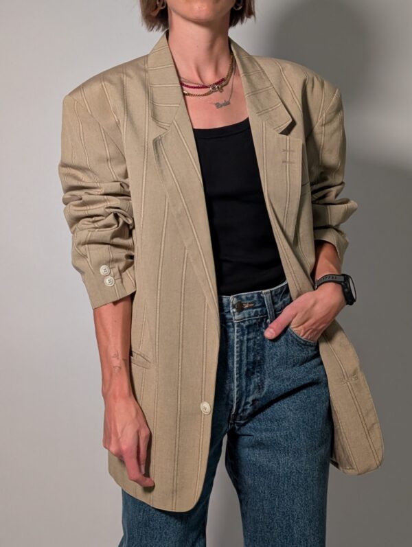 Sand stripe 03 Vintage beige blazer met subtiele verticale glansstrepen, klassieke revers en rechte licht oversized pasvorm.