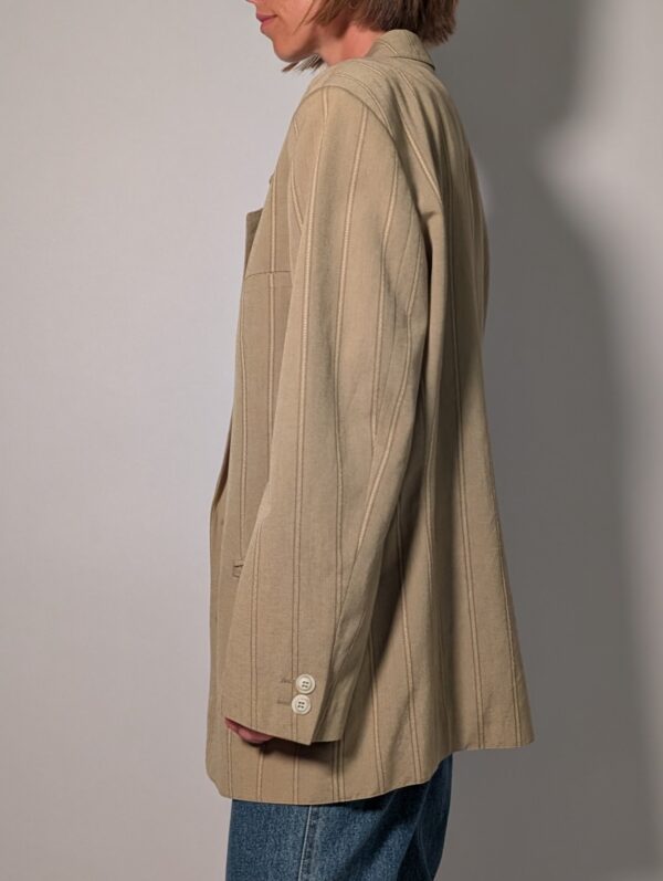 Sand stripe 05 Vintage beige blazer met subtiele verticale glansstrepen, klassieke revers en rechte licht oversized pasvorm.