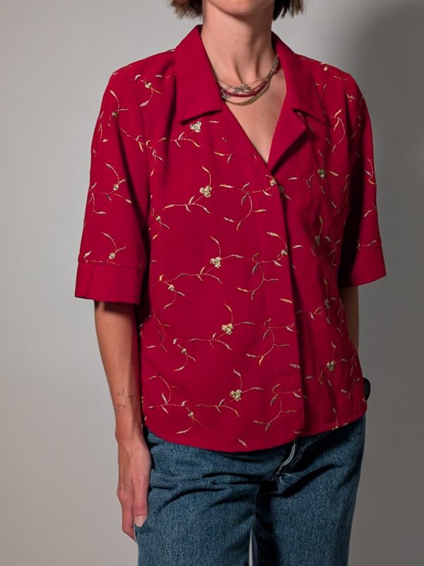 Scarlet stitch 01 Vintage rode blouse met korte mouwen, klassieke kraag en subtiel goudkleurig bloem- en rankborduurwerk.